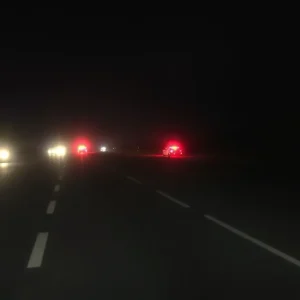 Nighttime view of a highway accident scene with emergency lights.